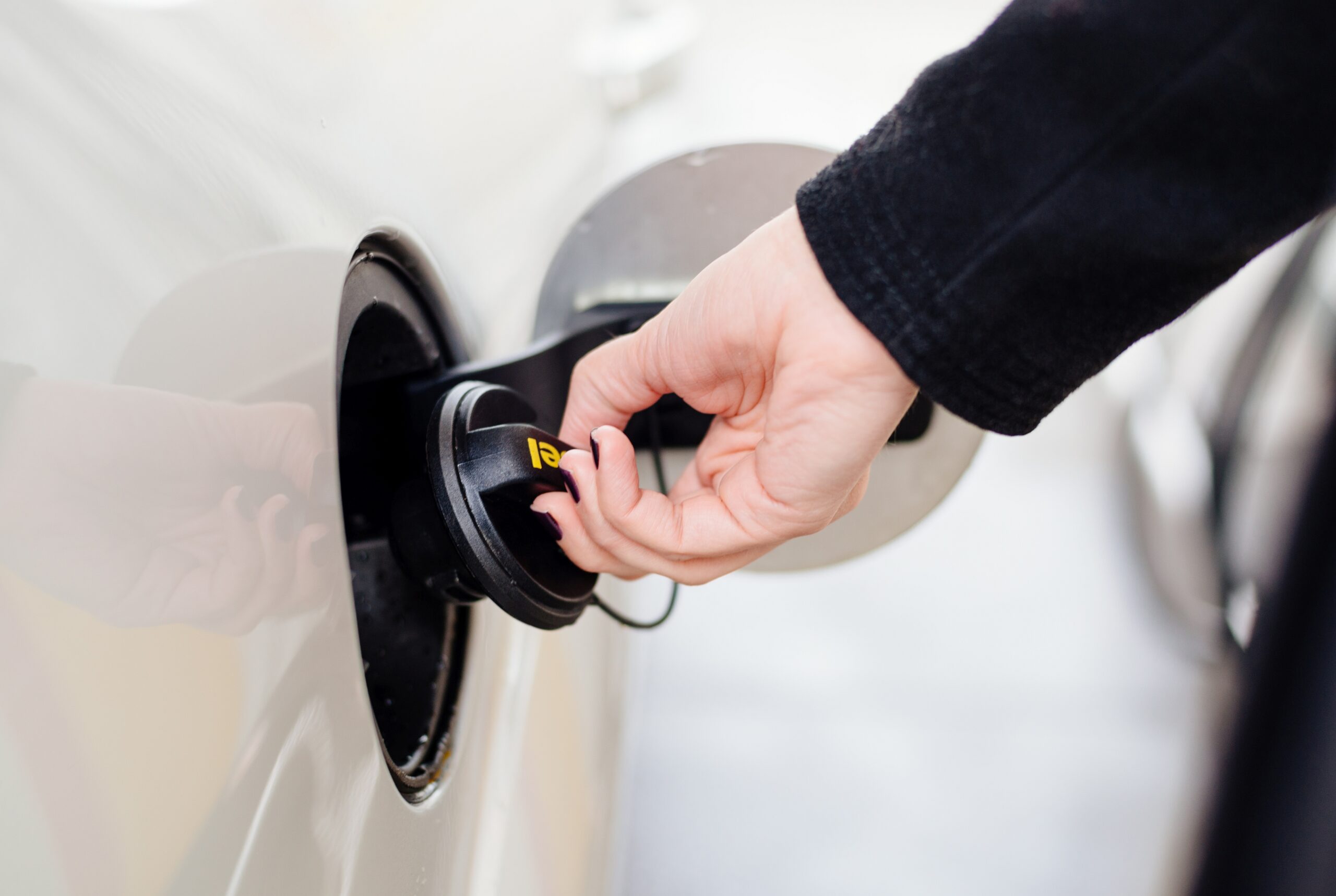 Woman opening the fuel cap on her car at the gas station.